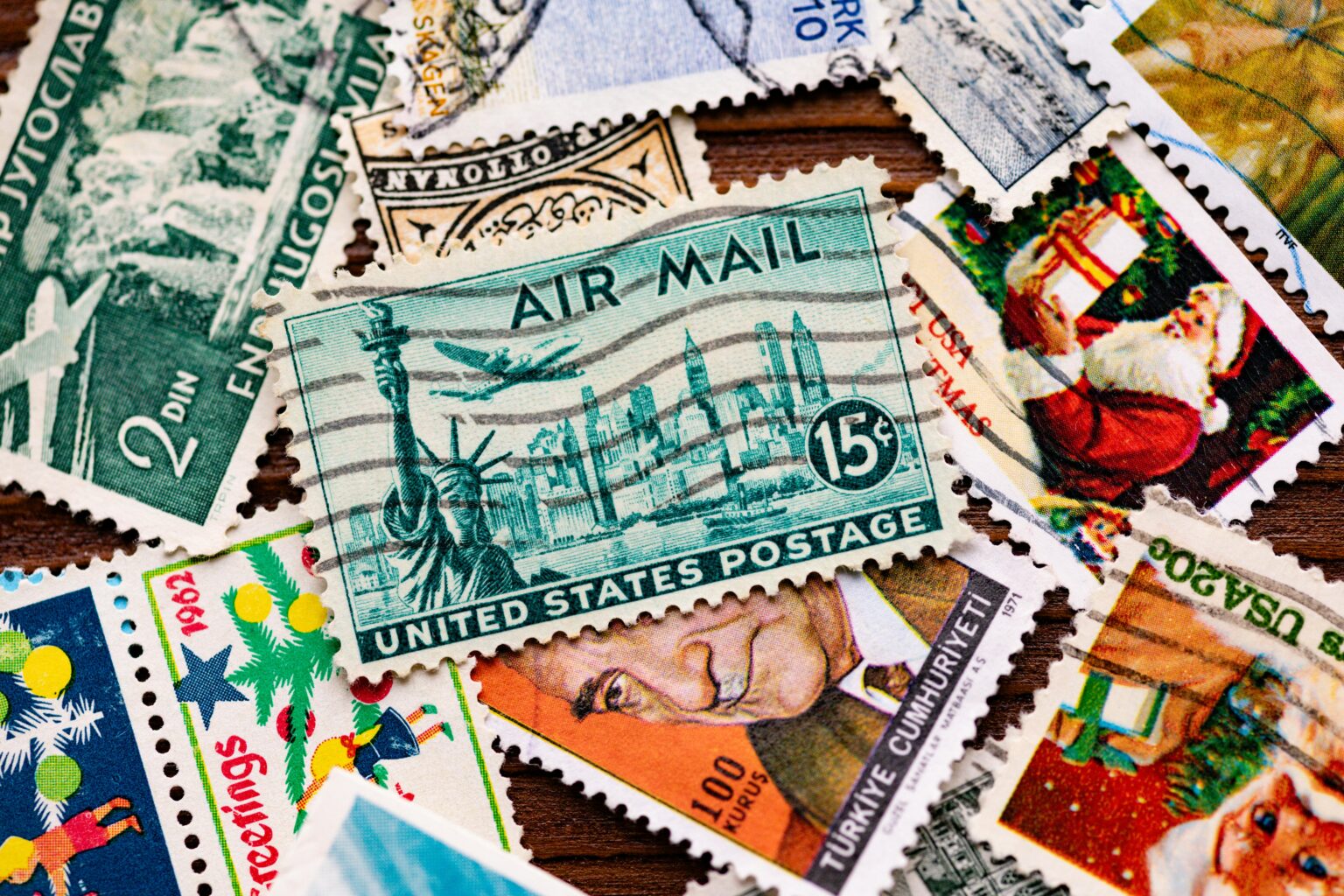 Colorful collage of overlapping postage stamps on a wooden surface, showing various designs and perforated edges.